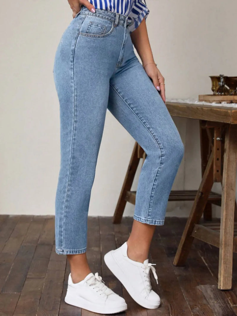 Person wearing blue jeans and white sneakers in a casual setting.