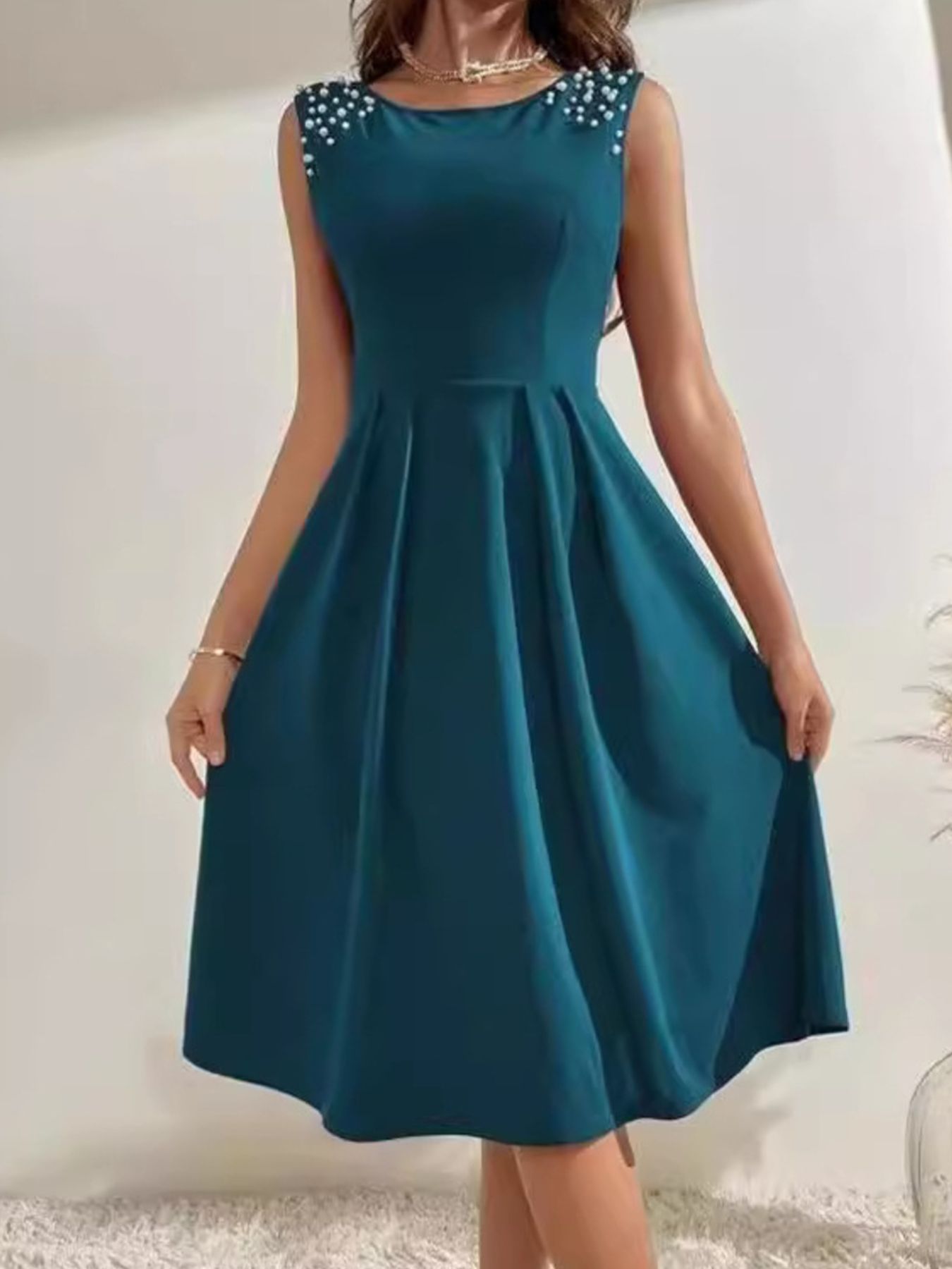 Teal dress with embellished shoulders on a plain background
