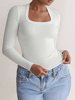 Person wearing a white long-sleeve top and light blue jeans on a plain background