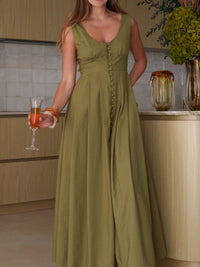 Woman in a green dress holding a drink in a kitchen setting