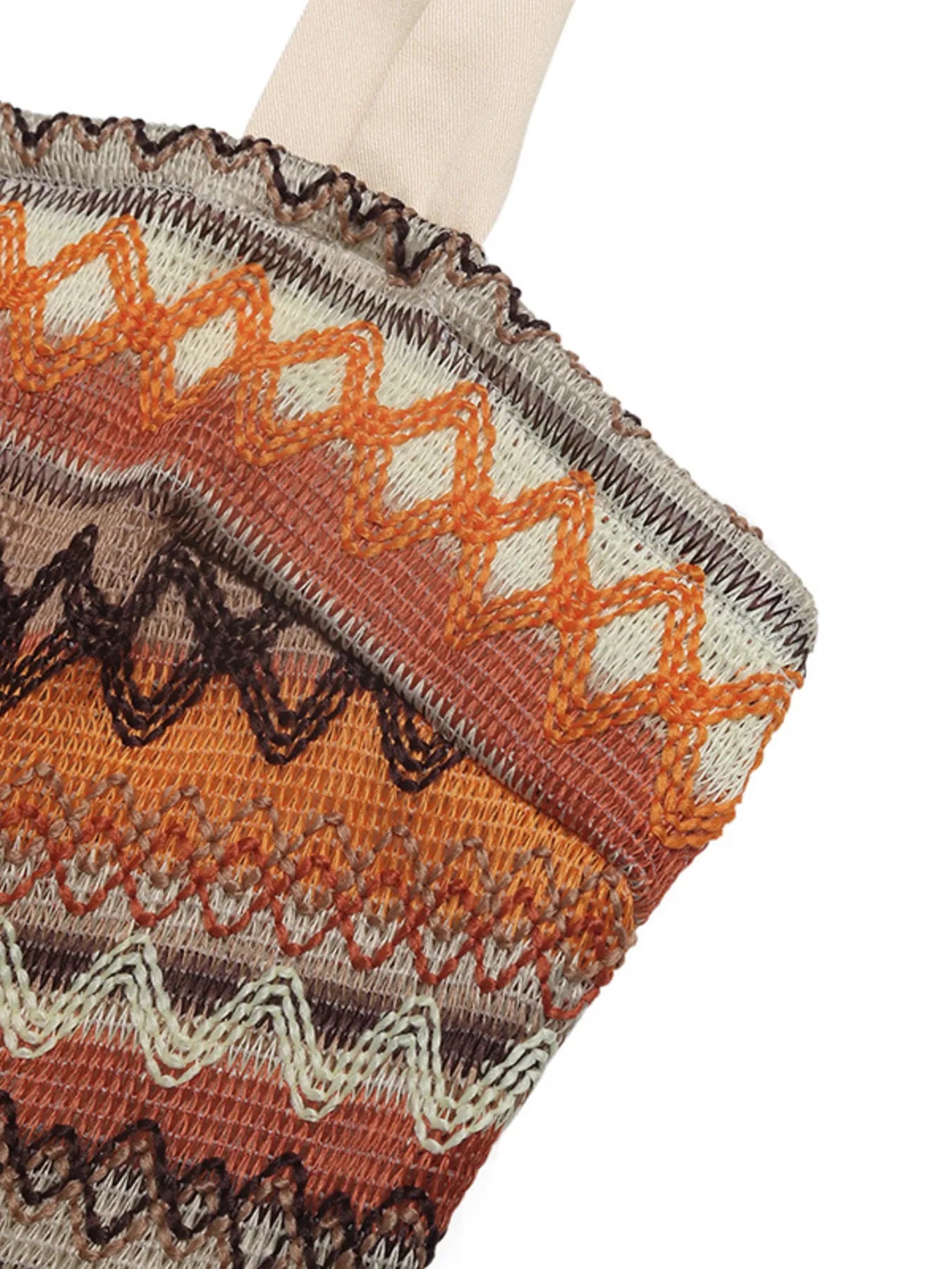 Close-up of a knitted fabric with a pattern featuring orange, brown, and beige colors on a white background.