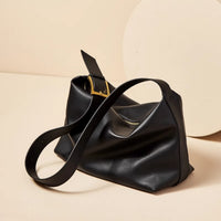 Black leather handbag with a strap on a beige background