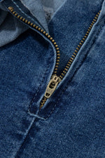 Close-up of a blue denim jacket with a gold zipper