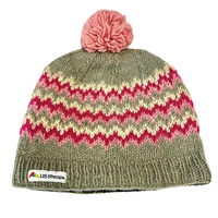 Knitted beanie with pink and green pattern and pom-pom on a white background