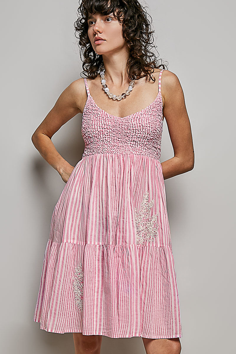 Woman wearing a pink striped dress with a plain background
