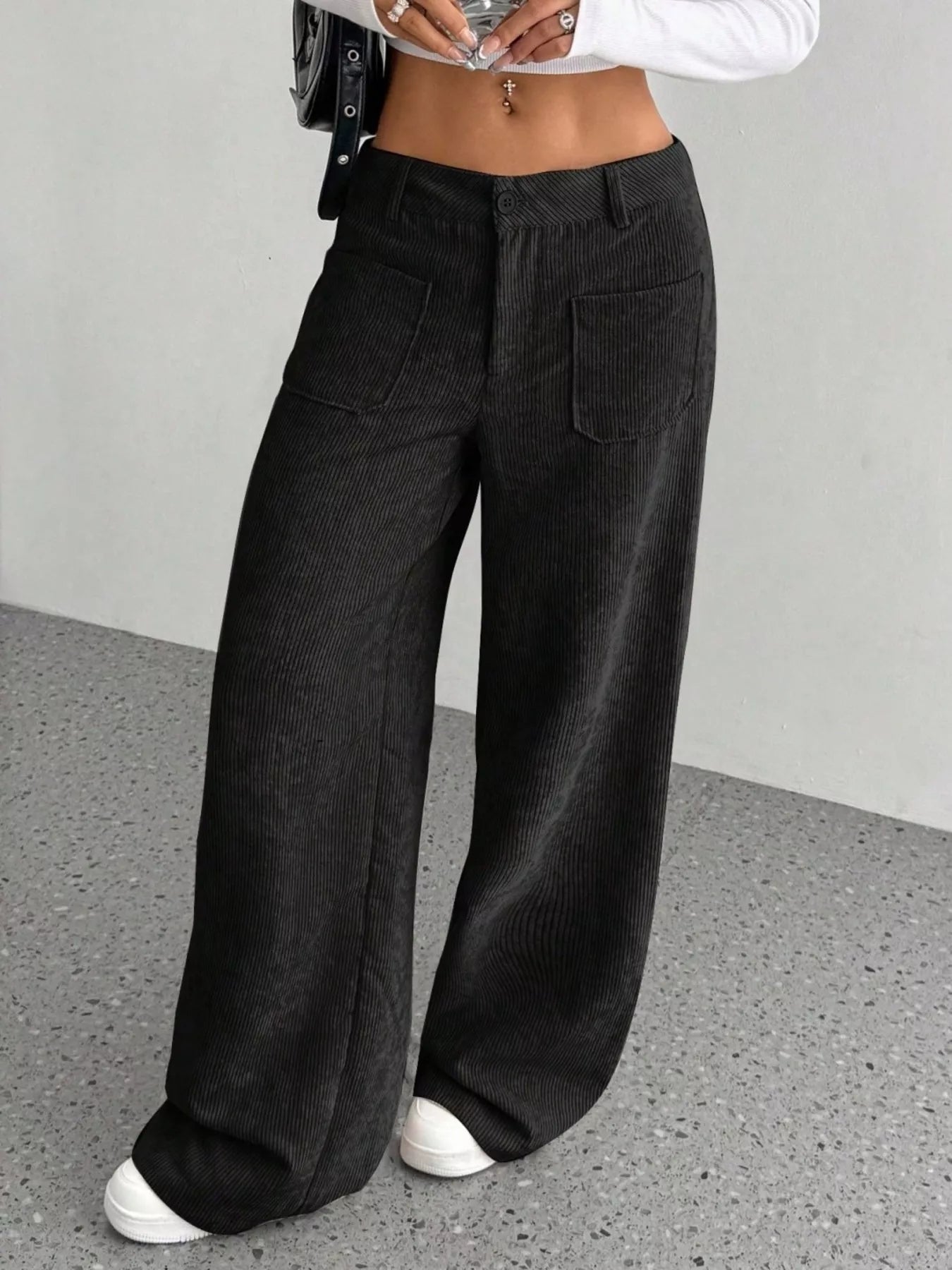 Person wearing black wide-leg pants on a gray floor with a neutral background