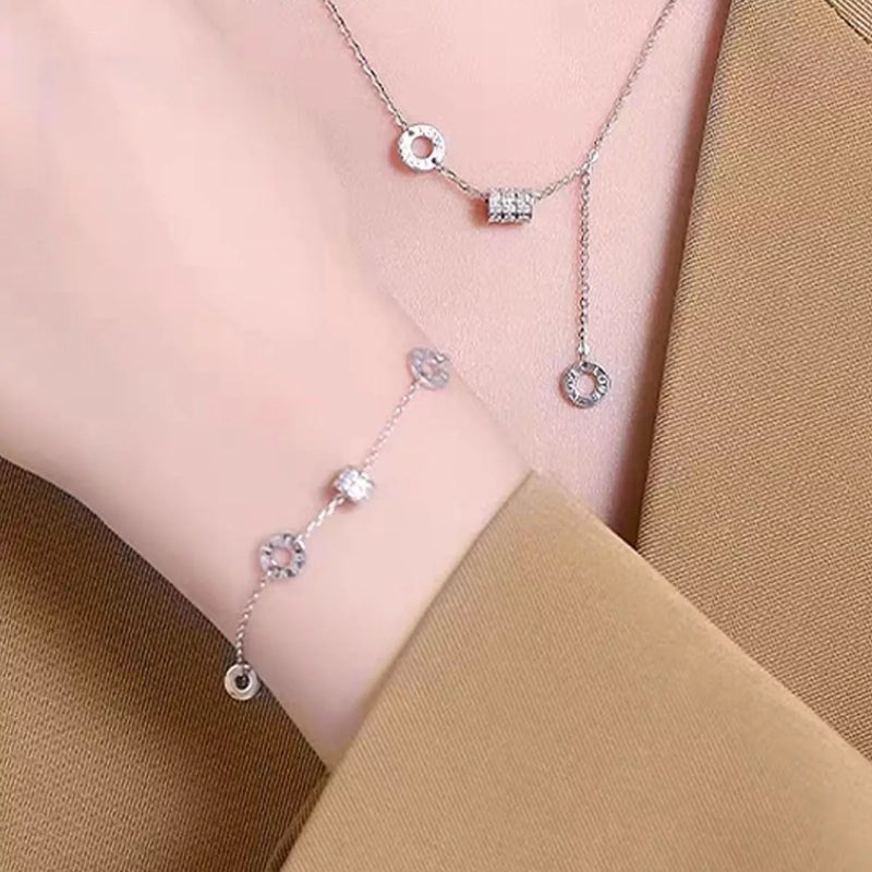 Silver necklace with circular pendants on a person wearing a beige top.