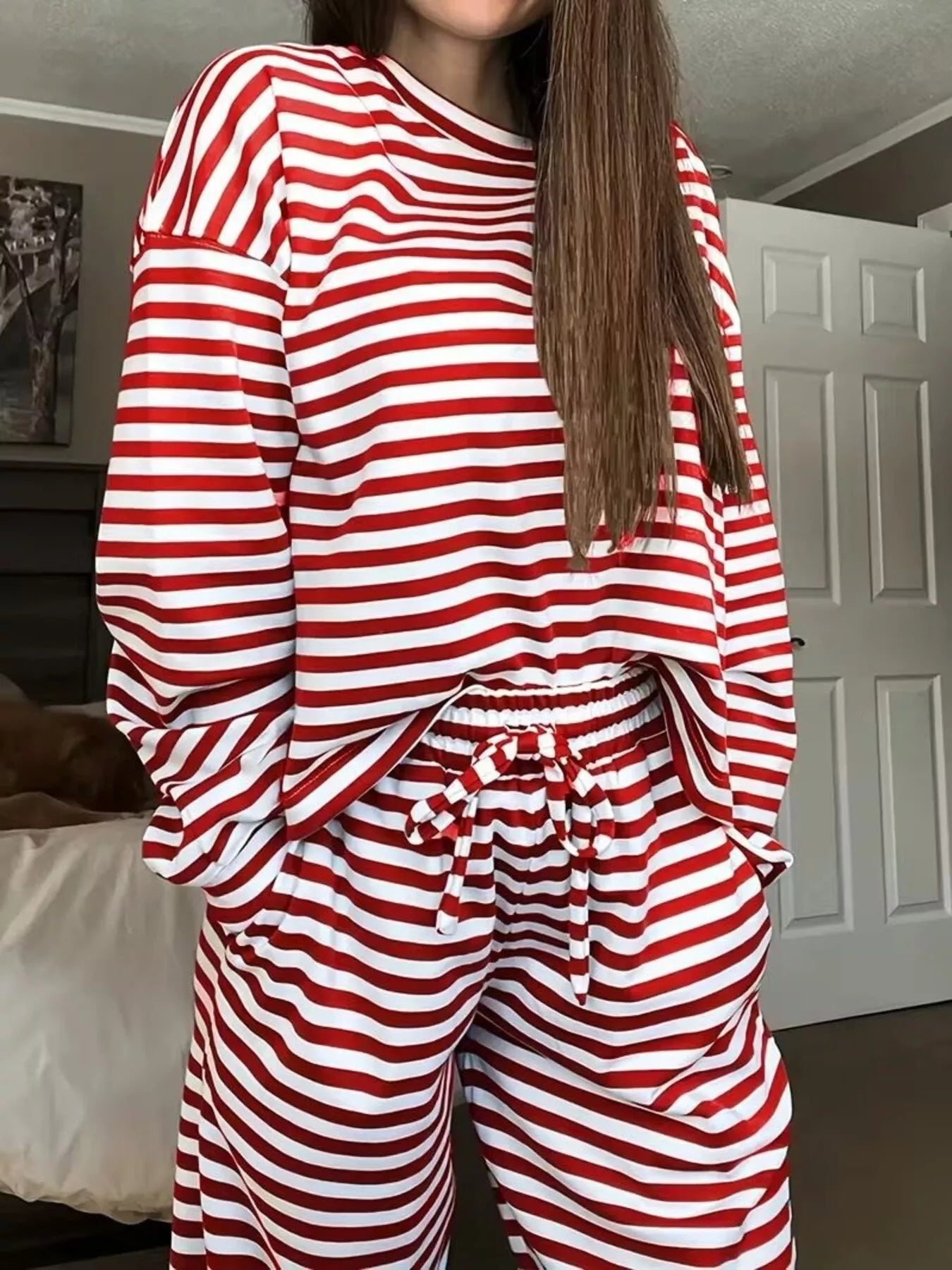 Person wearing red and white striped pajamas in a room.