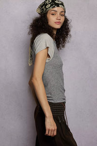 Woman wearing a gray t-shirt and black pants against a plain background