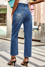Person wearing blue jeans walking on a city street.