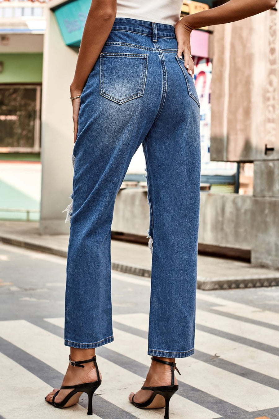 Person wearing blue jeans walking on a city street.