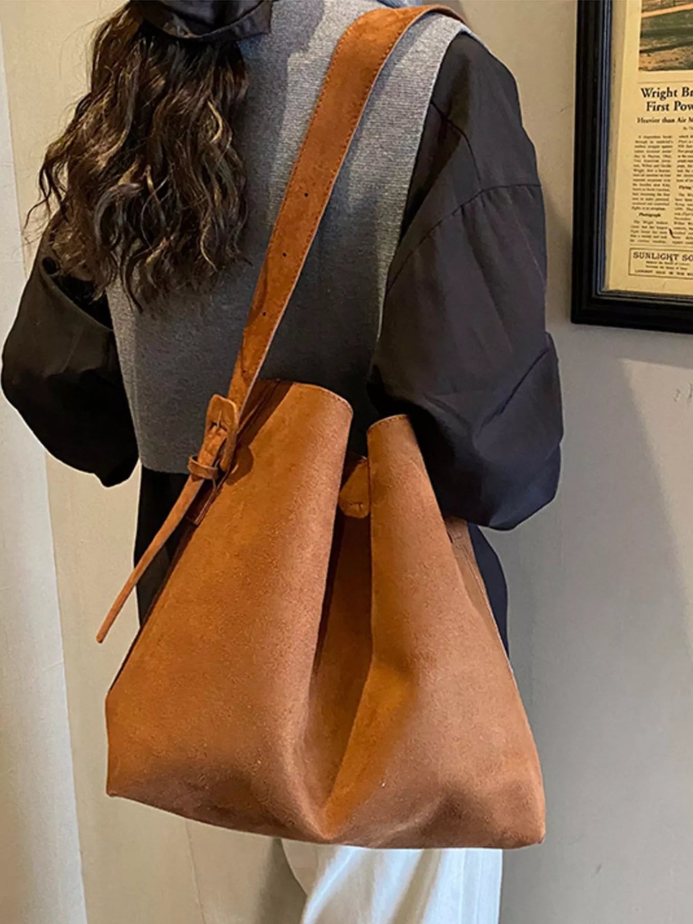 Person holding a brown leather bag indoors