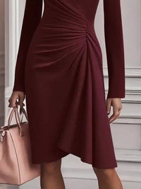 Maroon dress with long sleeves and a pink handbag held by a person.