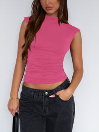 Person wearing a pink sleeveless top and black pants against a white background