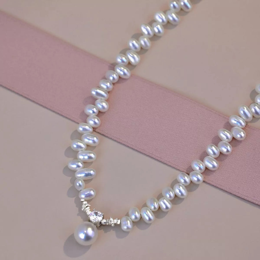 Pearl necklace with a diamond clasp on a pink and beige background
