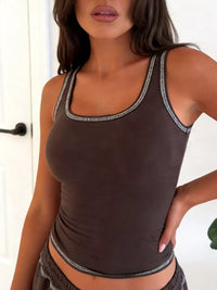 Woman wearing a brown tank top with decorative trim in a casual setting.
