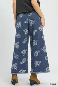 Blue paisley-patterned jeans worn by a person on a white background