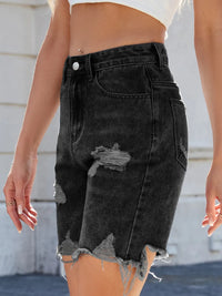 Black denim shorts with distressed details worn by a person.