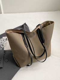 Brown tote bag with black handles on a white surface