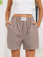 Brown and white checkered shorts with 'Vogue' branding worn by a person.