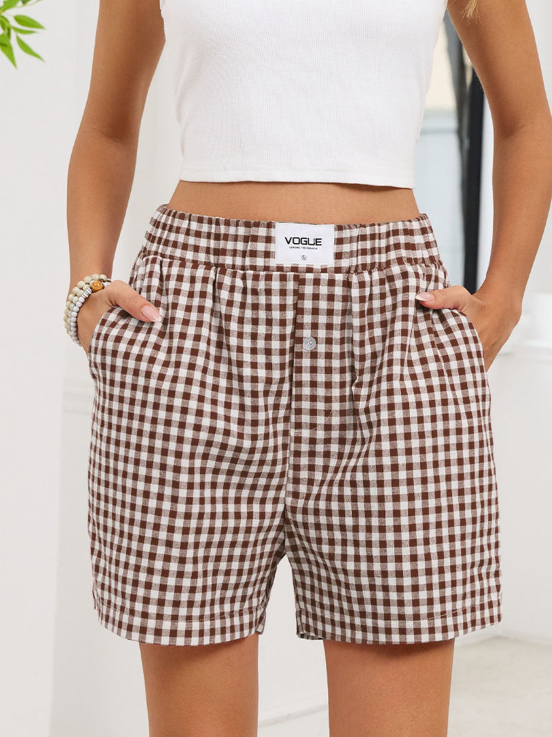 Brown and white checkered shorts with 'Vogue' branding worn by a person.