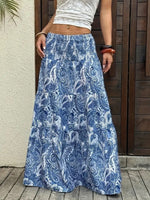 Person wearing a blue paisley patterned skirt standing against a wooden door.
