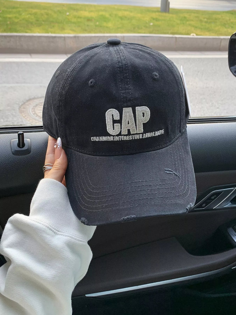 Black cap with 'CAP' branding held inside a car.