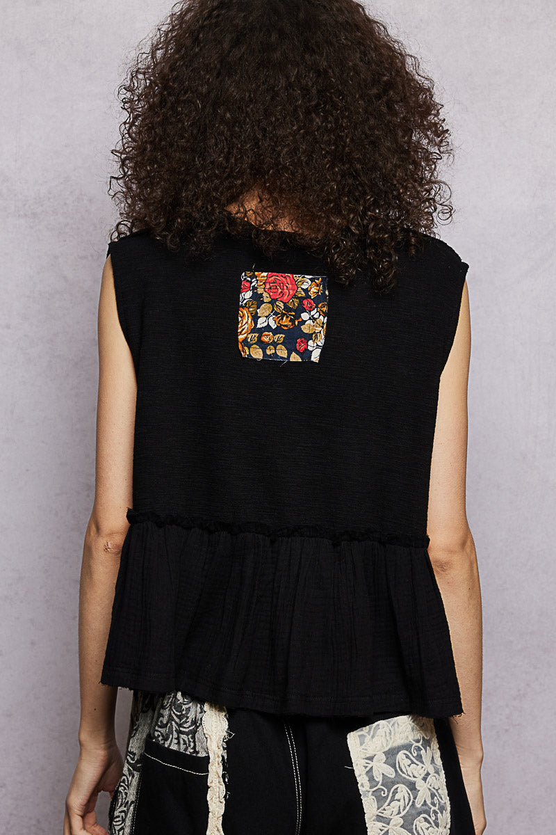 Person wearing a black sleeveless top with a colorful pocket on a gray background