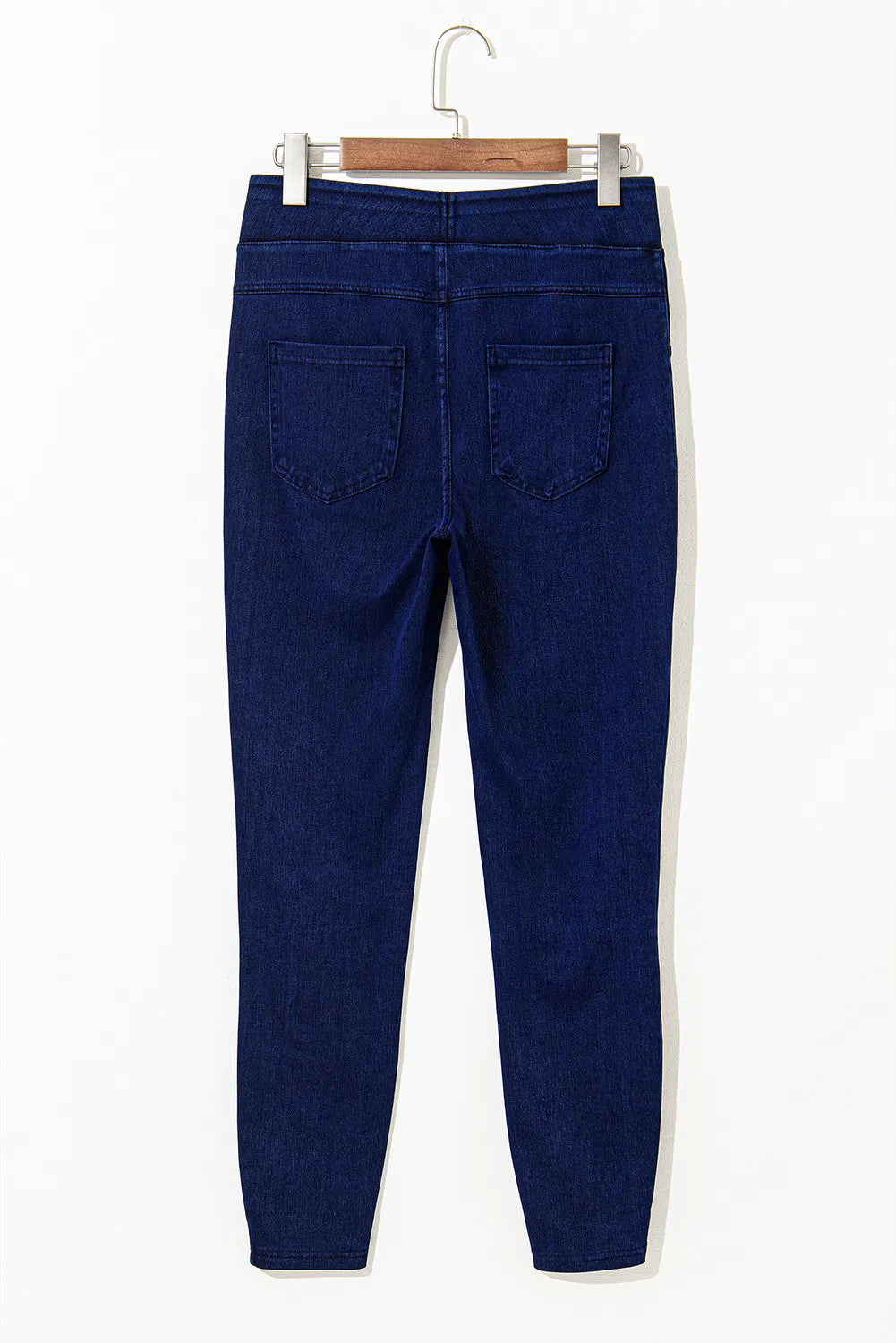 Blue jeans on a hanger against a white background