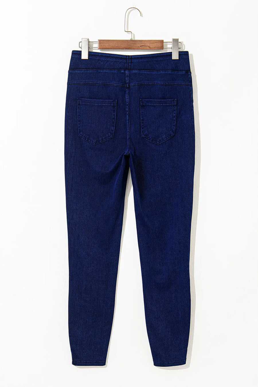 Blue jeans on a hanger against a white background