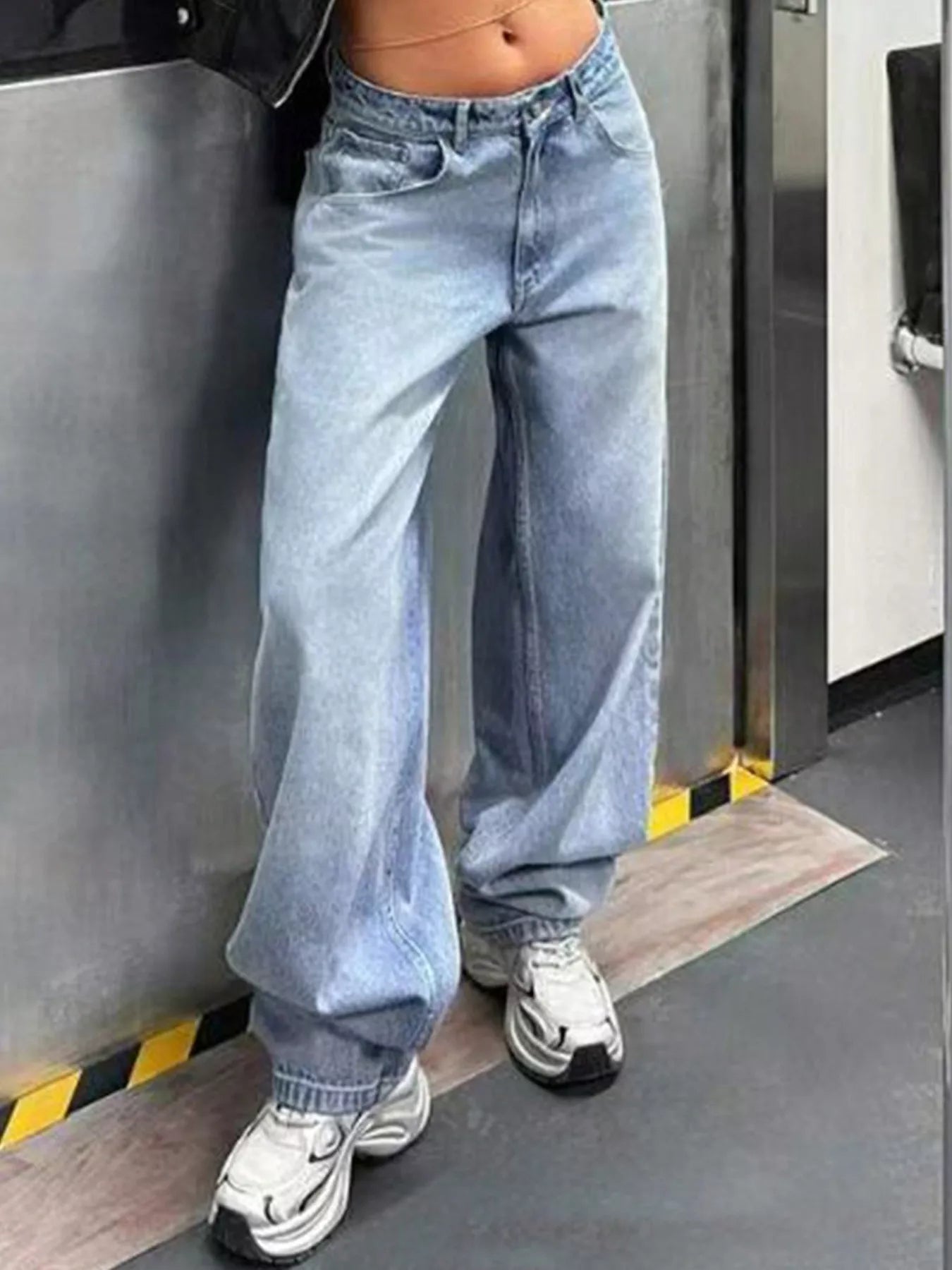 Person wearing light blue jeans and white sneakers in a metallic setting