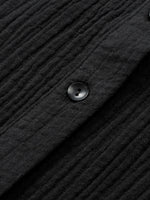 Close-up of a textured black fabric with a button on a dark background