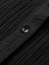 Close-up of a textured black fabric with a button on a dark background