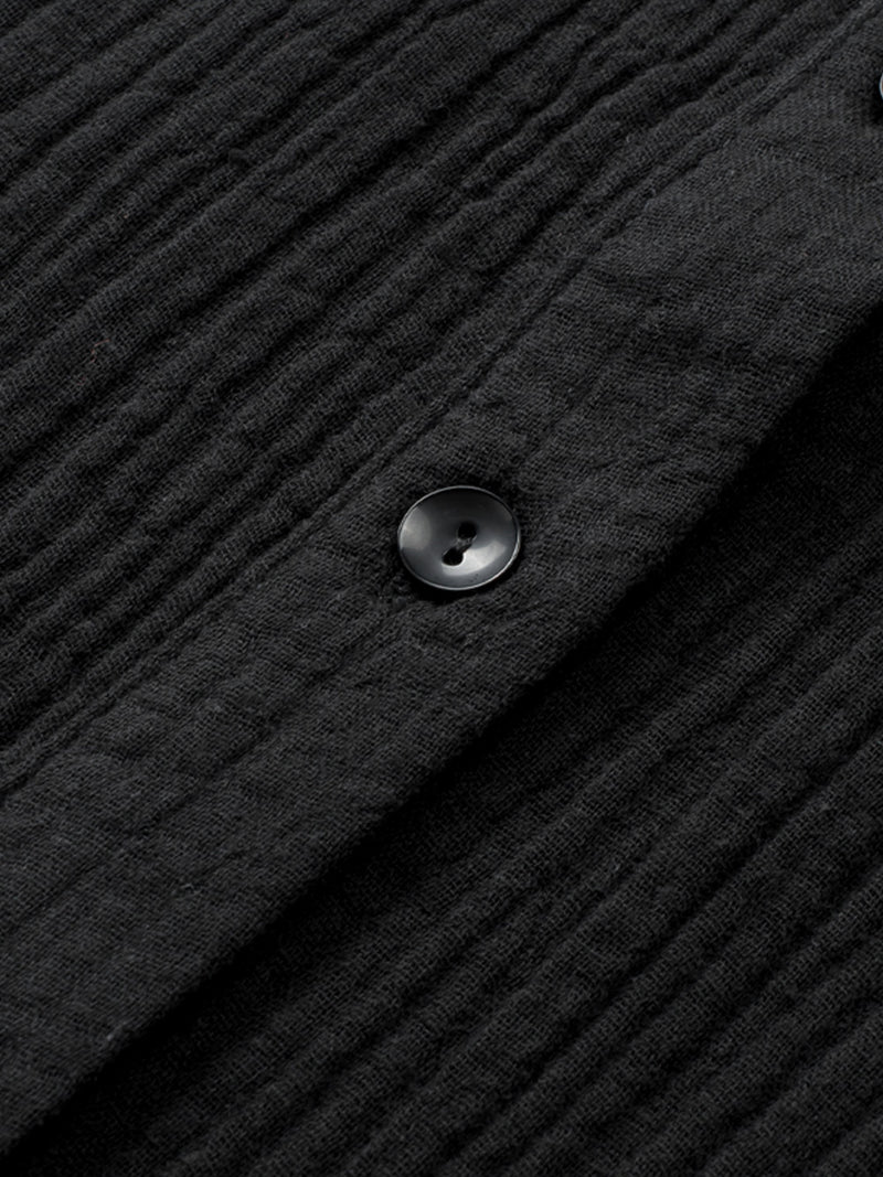Close-up of a textured black fabric with a button on a dark background