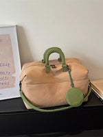 Tan duffel bag with green handles and strap on a surface