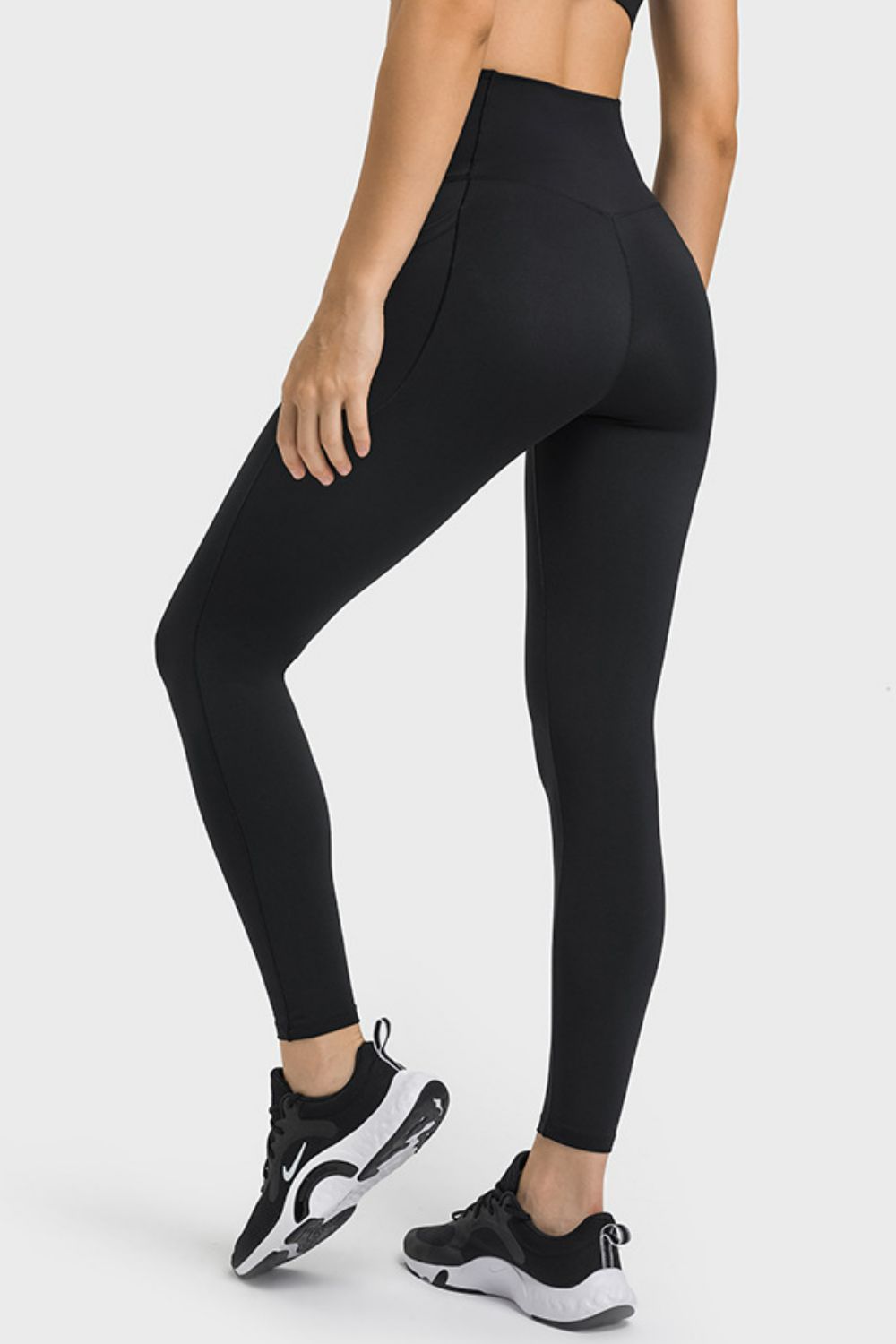 Person wearing black leggings and black athletic shoes on a white background