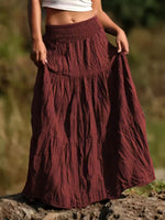 Person wearing a burgundy skirt with a blurred natural background