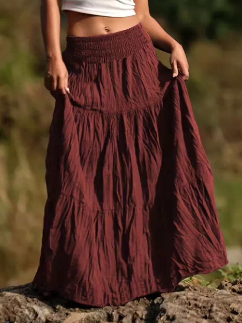 Person wearing a burgundy skirt with a blurred natural background