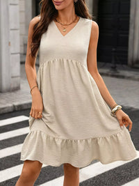 Woman wearing a beige sleeveless dress on a city street.