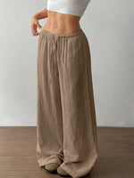 Person wearing brown wide-leg pants against a plain background