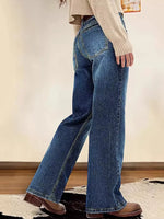 Person wearing blue jeans and a beige sweater in a minimal indoor setting