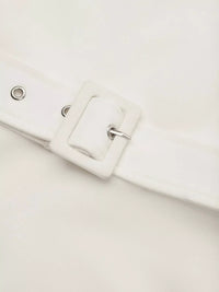 Close-up of a white belt with a buckle on a light gray background