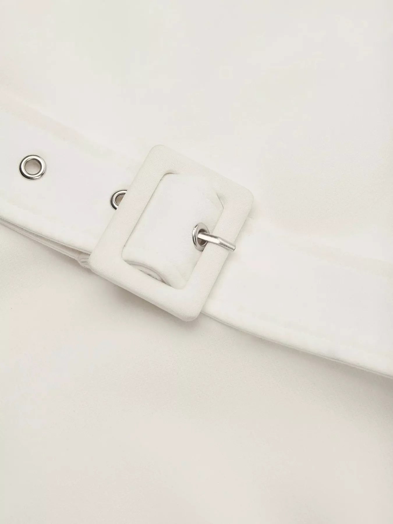 Close-up of a white belt with a buckle on a light gray background