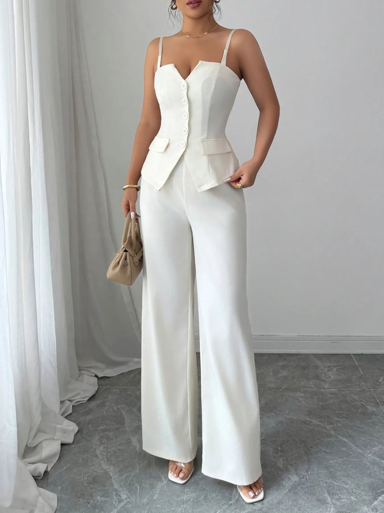 Woman wearing a white outfit with a blazer and wide-leg pants in a minimalistic setting.