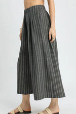Person wearing a black and white striped wide-leg pants on a plain background