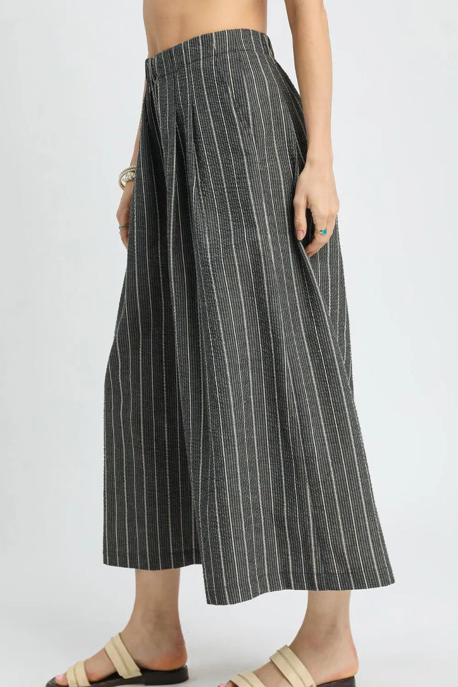 Person wearing a black and white striped wide-leg pants on a plain background