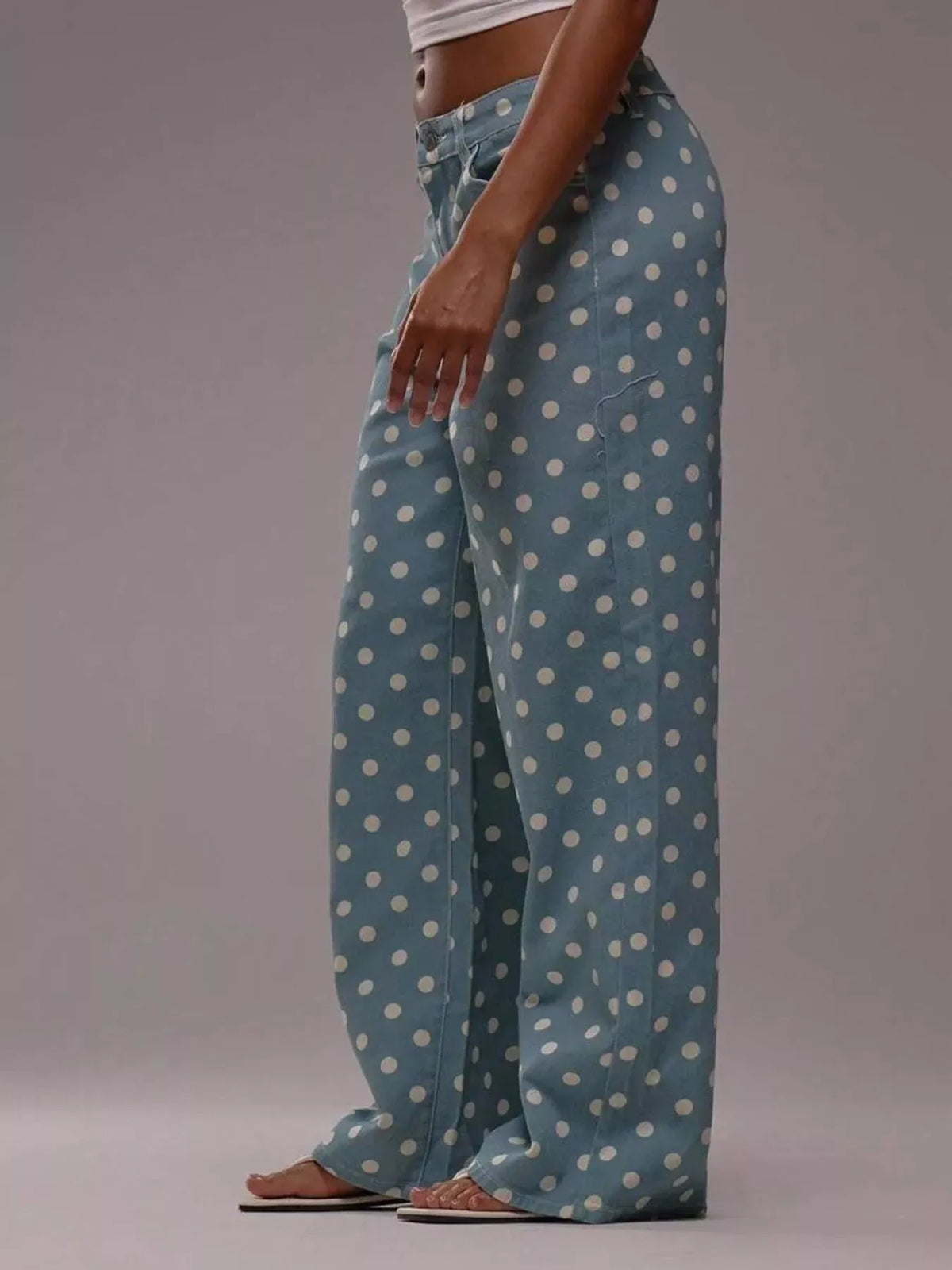 Blue pants with white polka dots worn by a person on a gray background