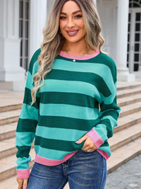 Woman wearing a green and pink striped sweater with a building in the background