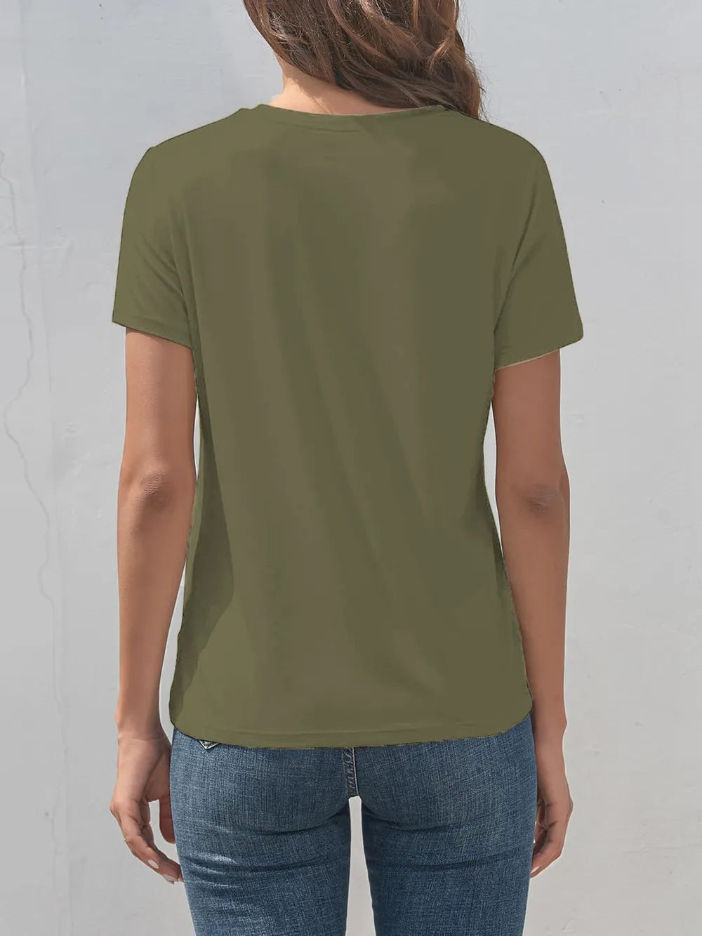 Person wearing a green t-shirt and blue jeans against a gray background