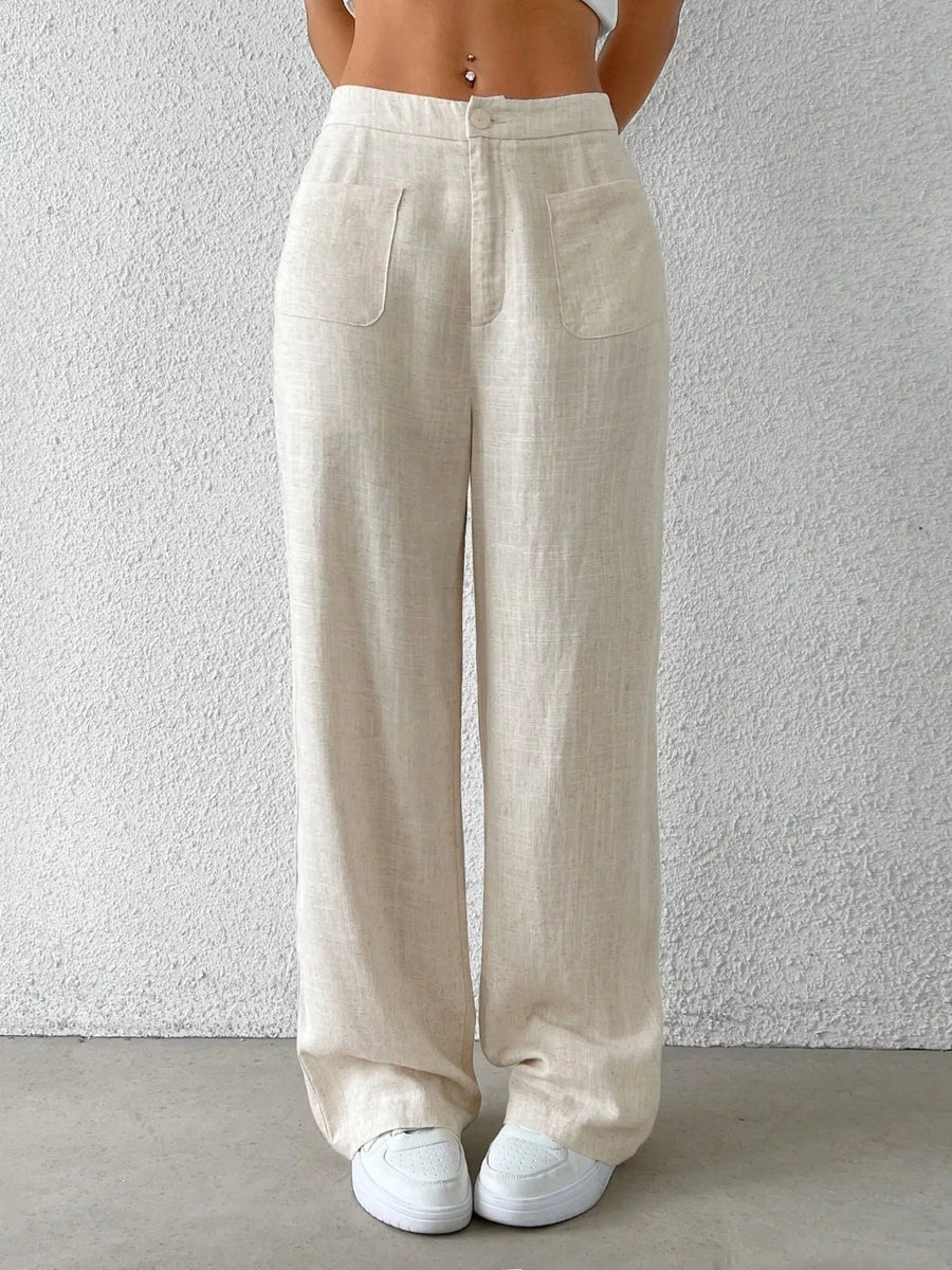 Beige linen pants worn by a person against a white wall.